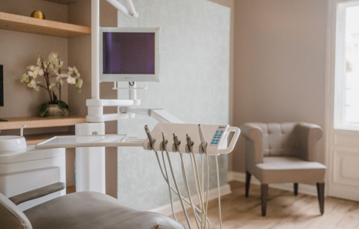 Behandlungszimmer bei achtzahn mit Zahnarztstuhl, Instrumenten und Sitzplatz am Fenster